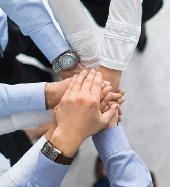 Team members joining hands, representing Adamsons' multidisciplinary engineering team